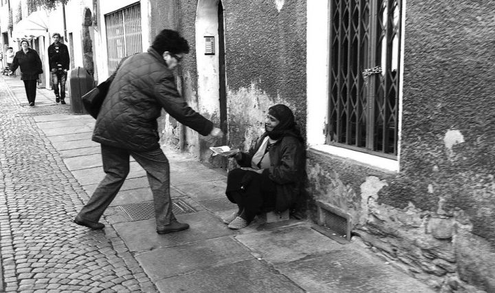 man gives money to beggar on street