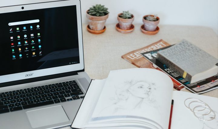An open book on a table with a laptop on the side
